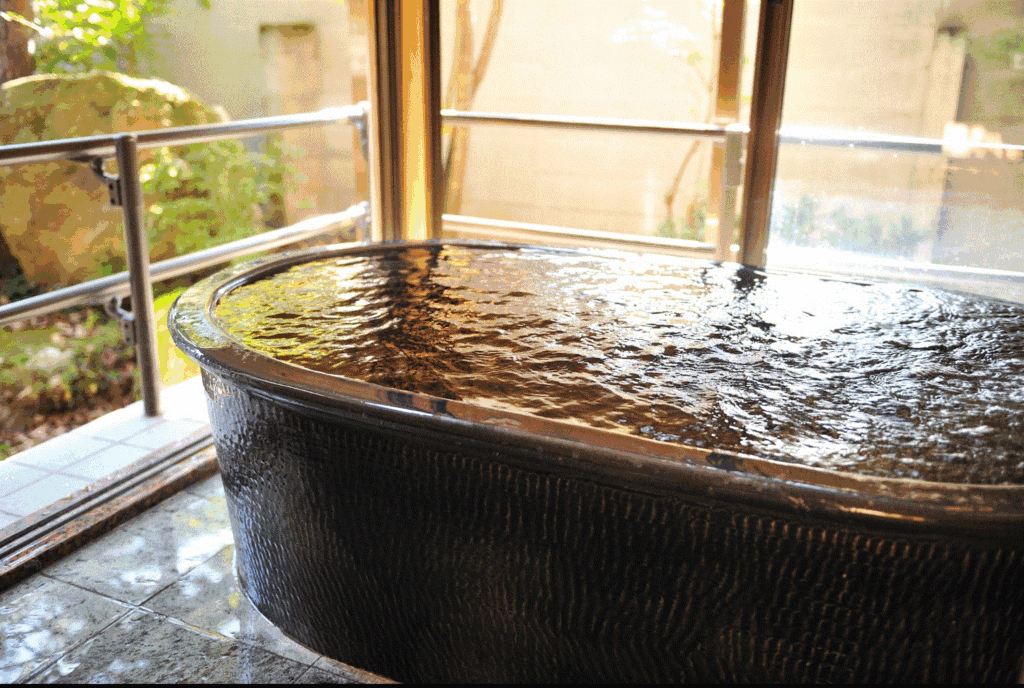 【かざぐるま】足下から生まれたての湯が陶器の湯船に湧き上がる。
